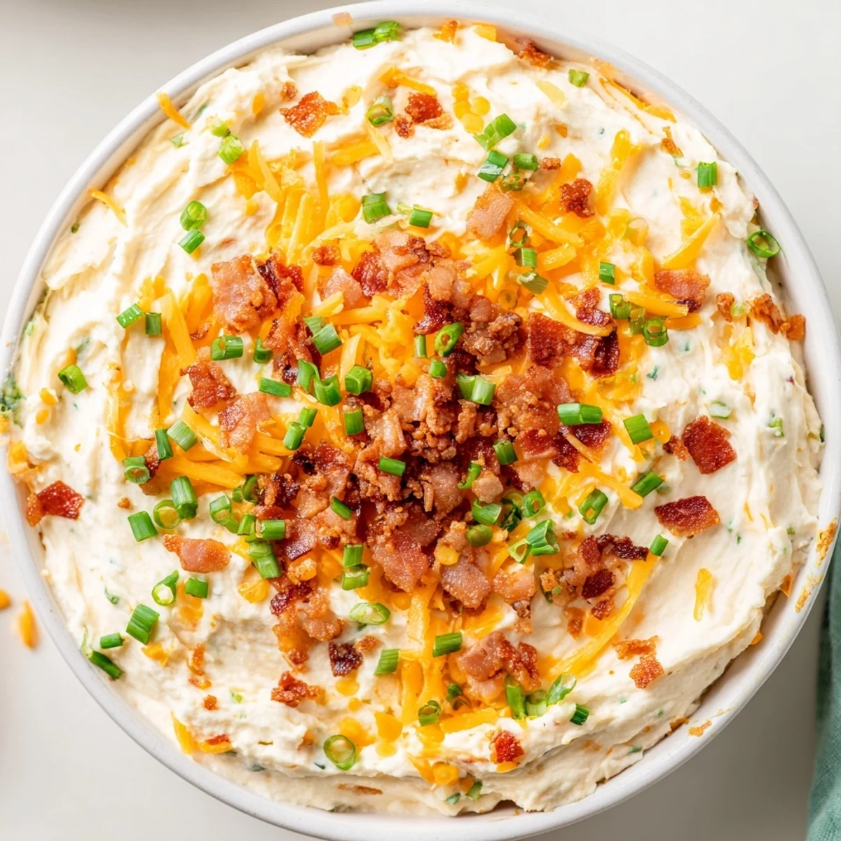 A creamy bowl of Loaded Baked Potato Dip topped with fresh chives and green onions, ready to scoop.