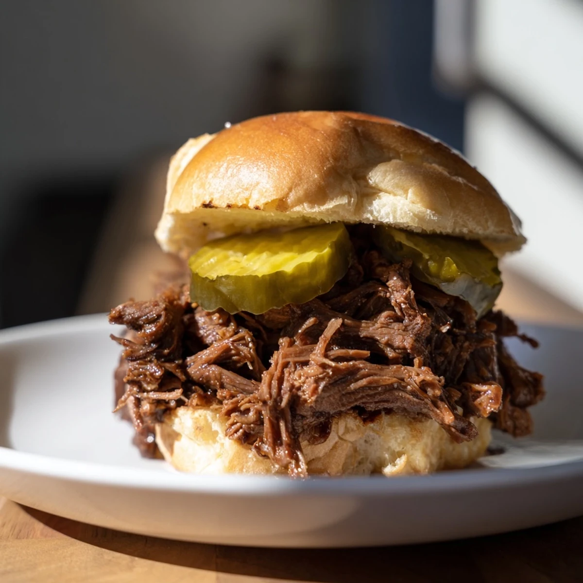 Slow-cooked, shredded beef piled high on soft slider buns, topped with tangy dill pickle slices for a savory bite.