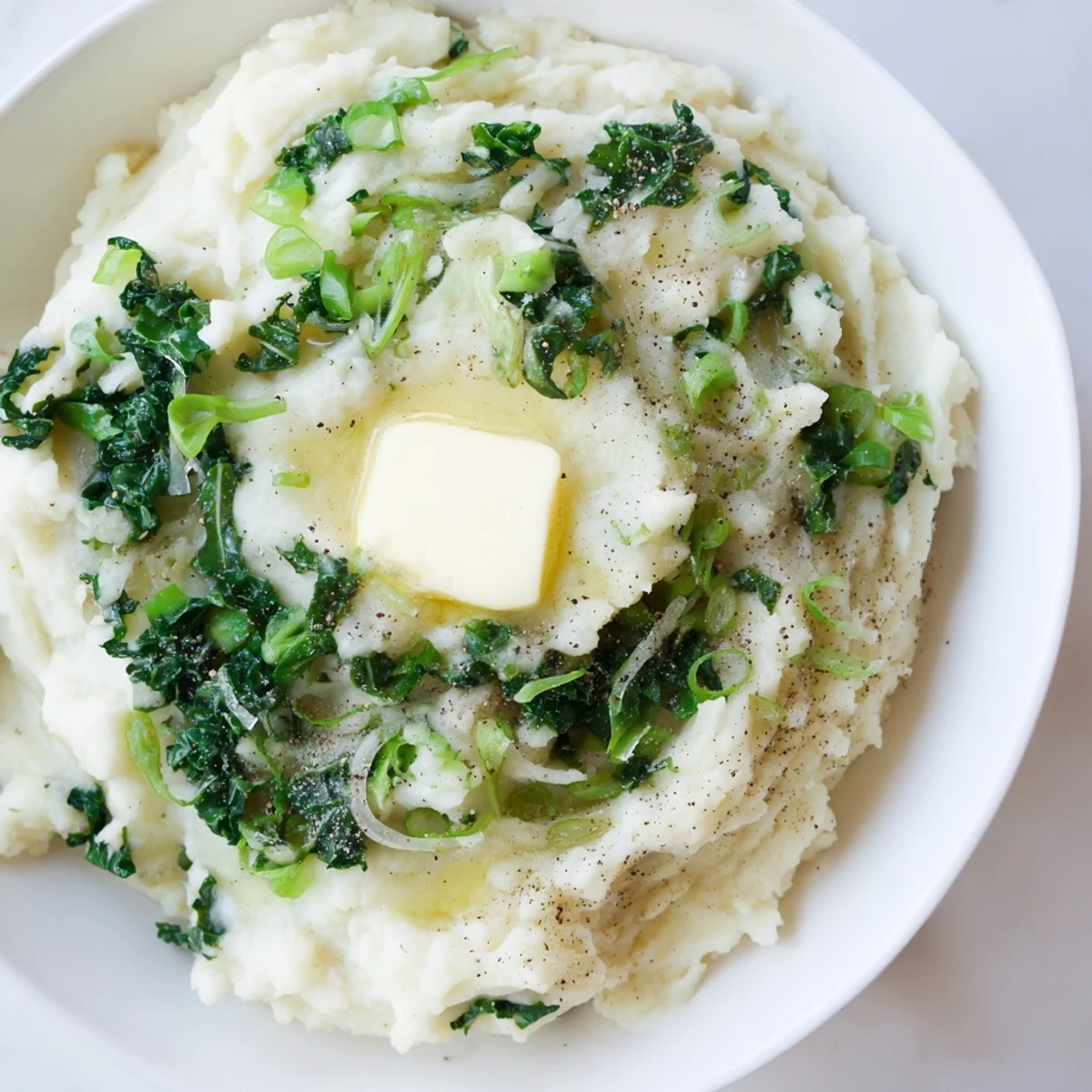 Rustic Irish Colcannon with kale and butter steaming in a white bowl, paired with a hearty main for a cozy St. Patrick's Day meal.
