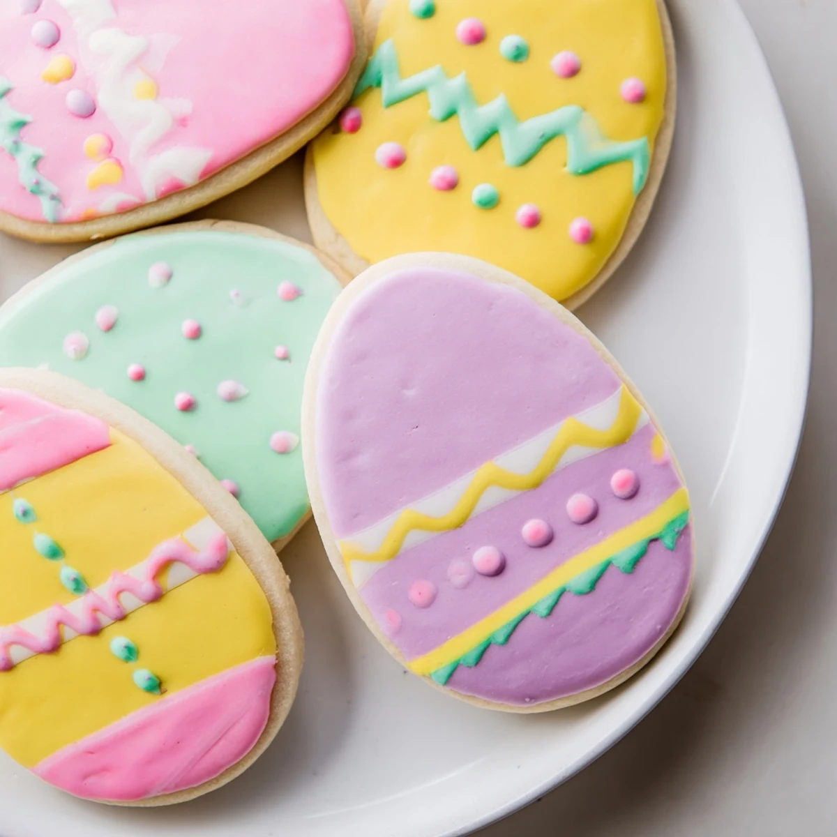 Close-up of decorated Easter Egg Sugar Cookies on a cooling rack, featuring delicate piping and cheerful pastel hues for a festive Easter dessert.