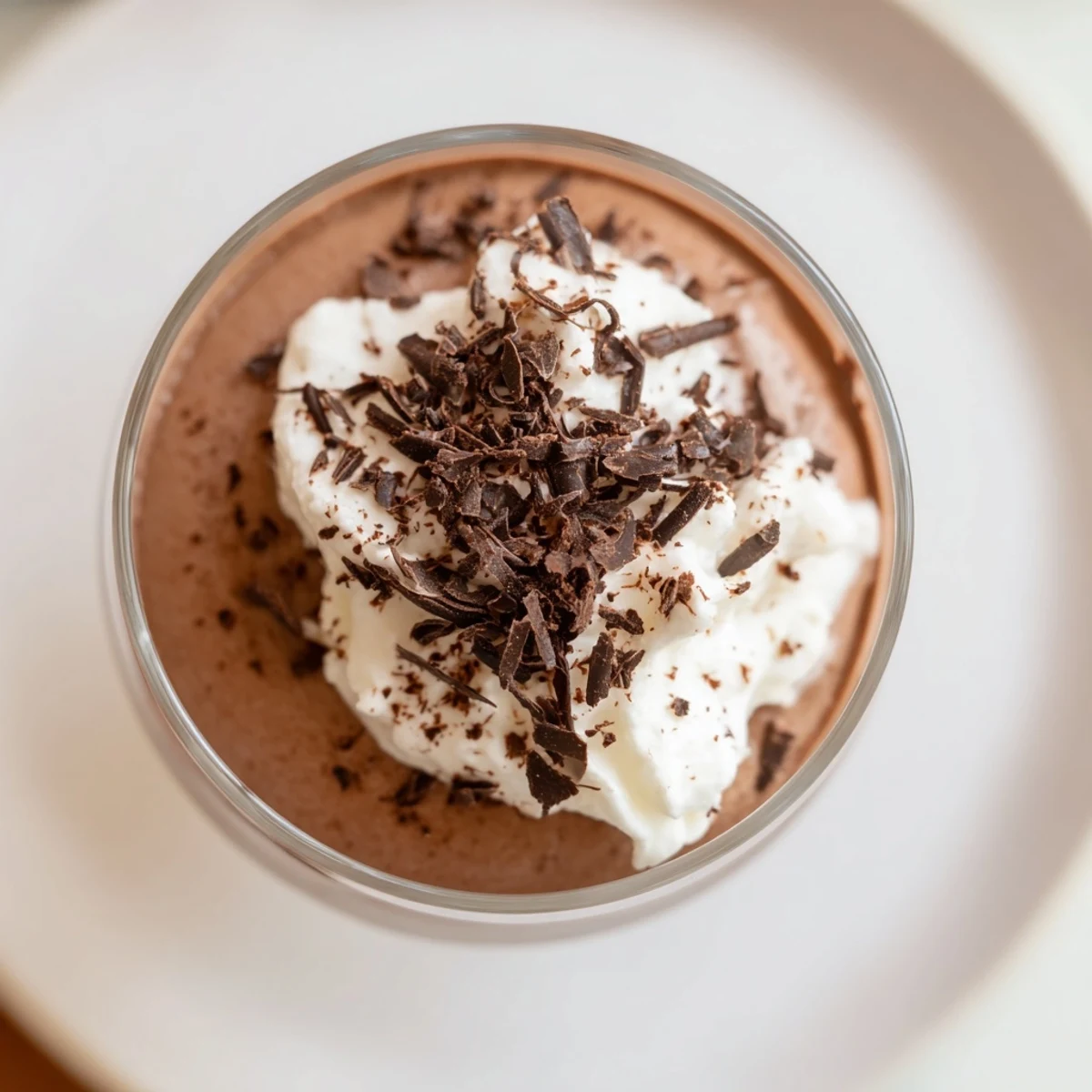 A close-up view of Chocolate Mousse with Whipped Cream, featuring delicate chocolate shavings garnish and a creamy texture in a dessert cup.