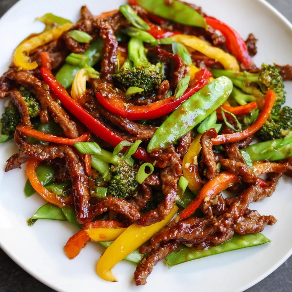 Vibrant red peppers and crisp broccoli in a glossy Spicy Beef Stir Fry with Mixed Vegetables served over steamed rice.