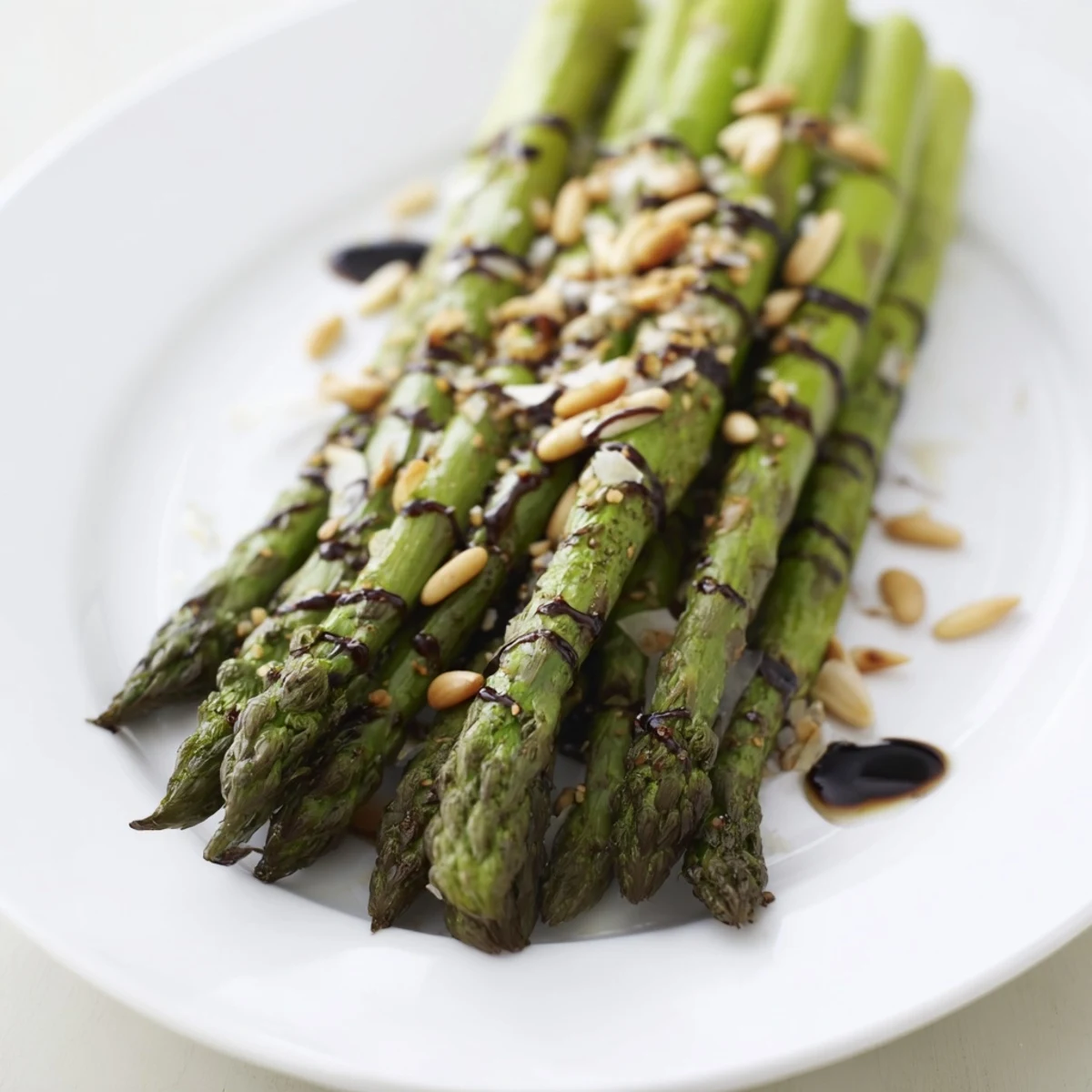 Close-up of roasted asparagus with balsamic reduction, highlighting glossy drizzle and shaved Parmesan garnish.