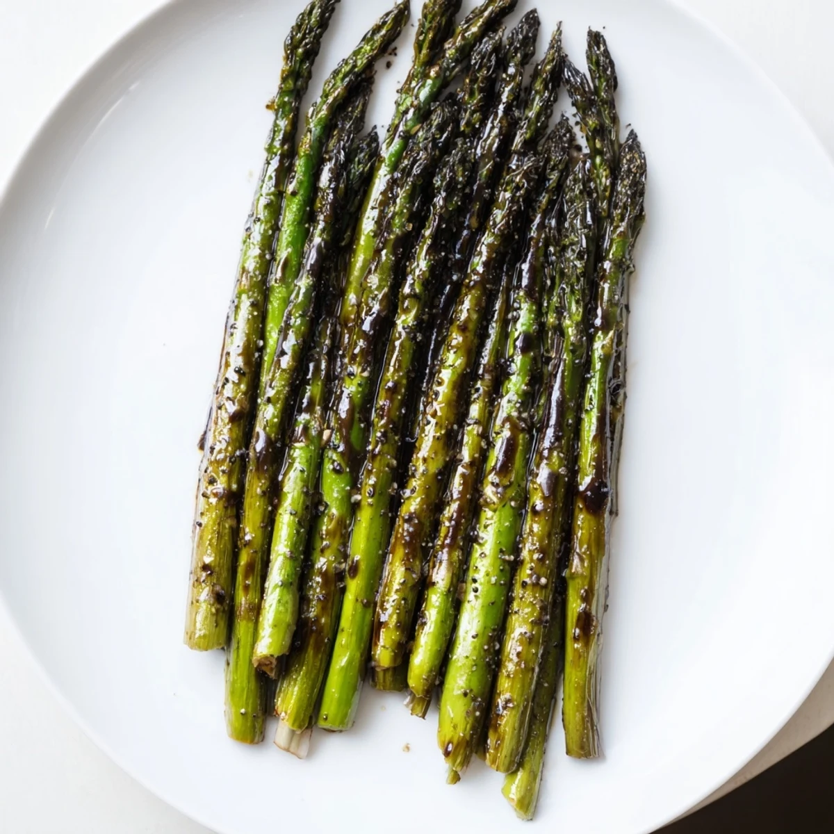 Perfectly roasted asparagus spears glisten with sweet balsamic glaze on a ceramic platter.