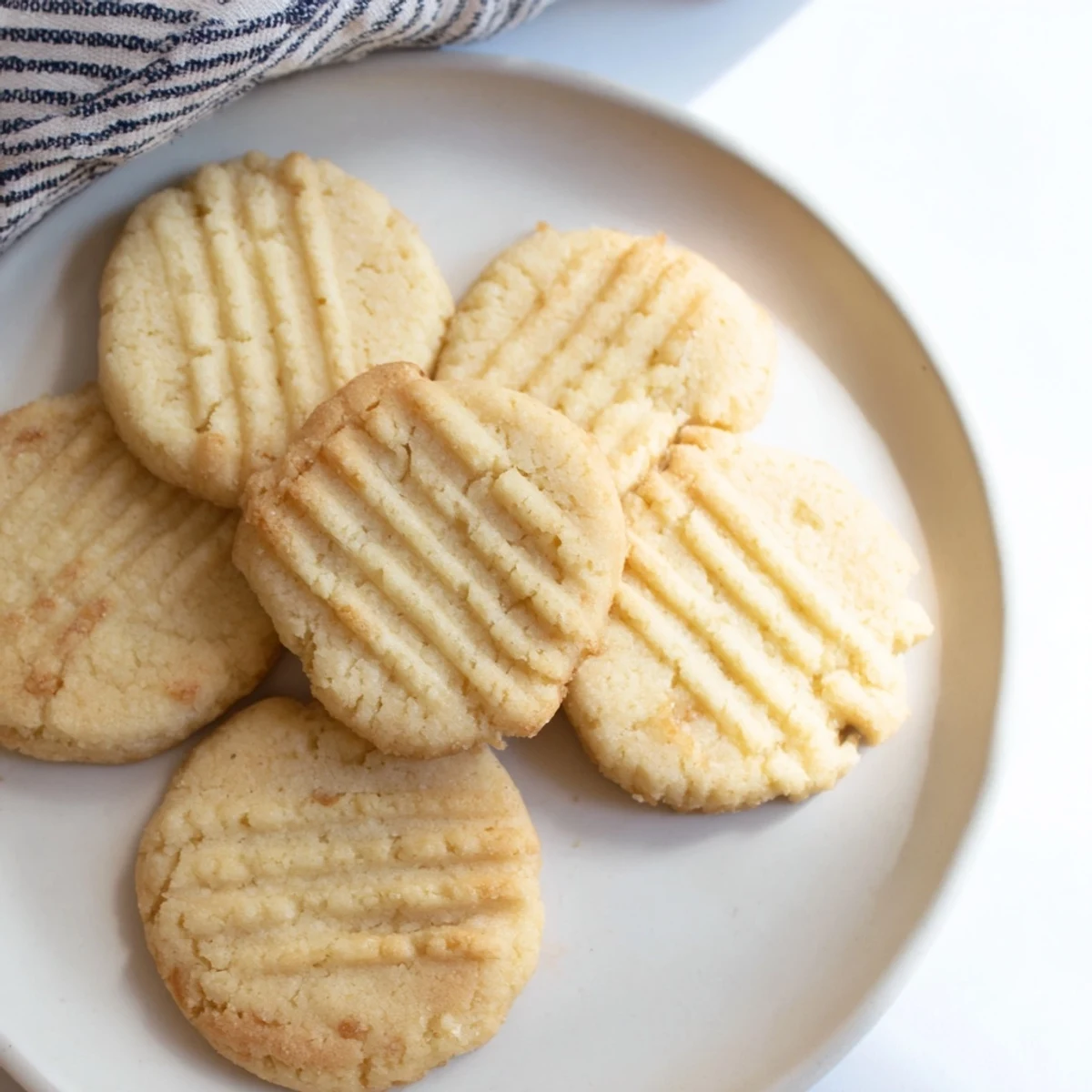 A plate of Keto Butter Cookies with a dusting of powdered sweetener, ready to be served with a glass of almond milk for keto-friendly snacking.