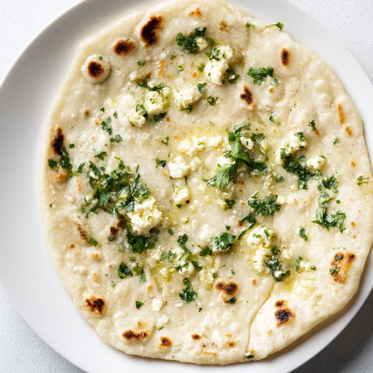 Warm Cottage Cheese Garlic Naan topped with fresh cilantro, perfect with curry.
