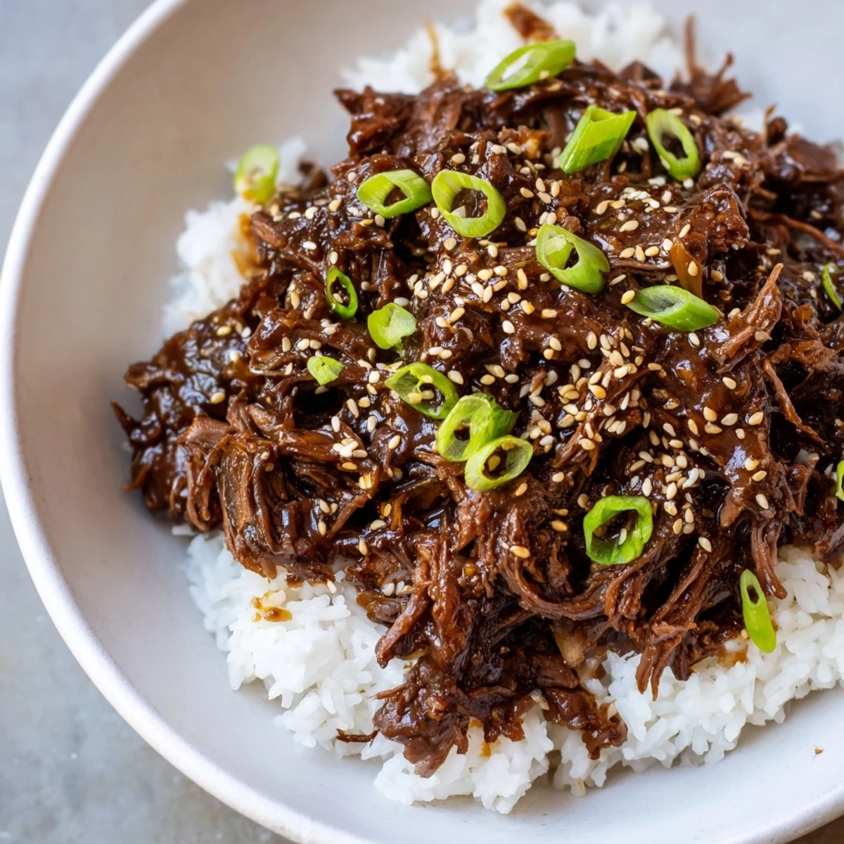 A close-up of a Slow Cooker Korean Beef bowl, featuring juicy meat glistening with sauce beside steamed vegetables.