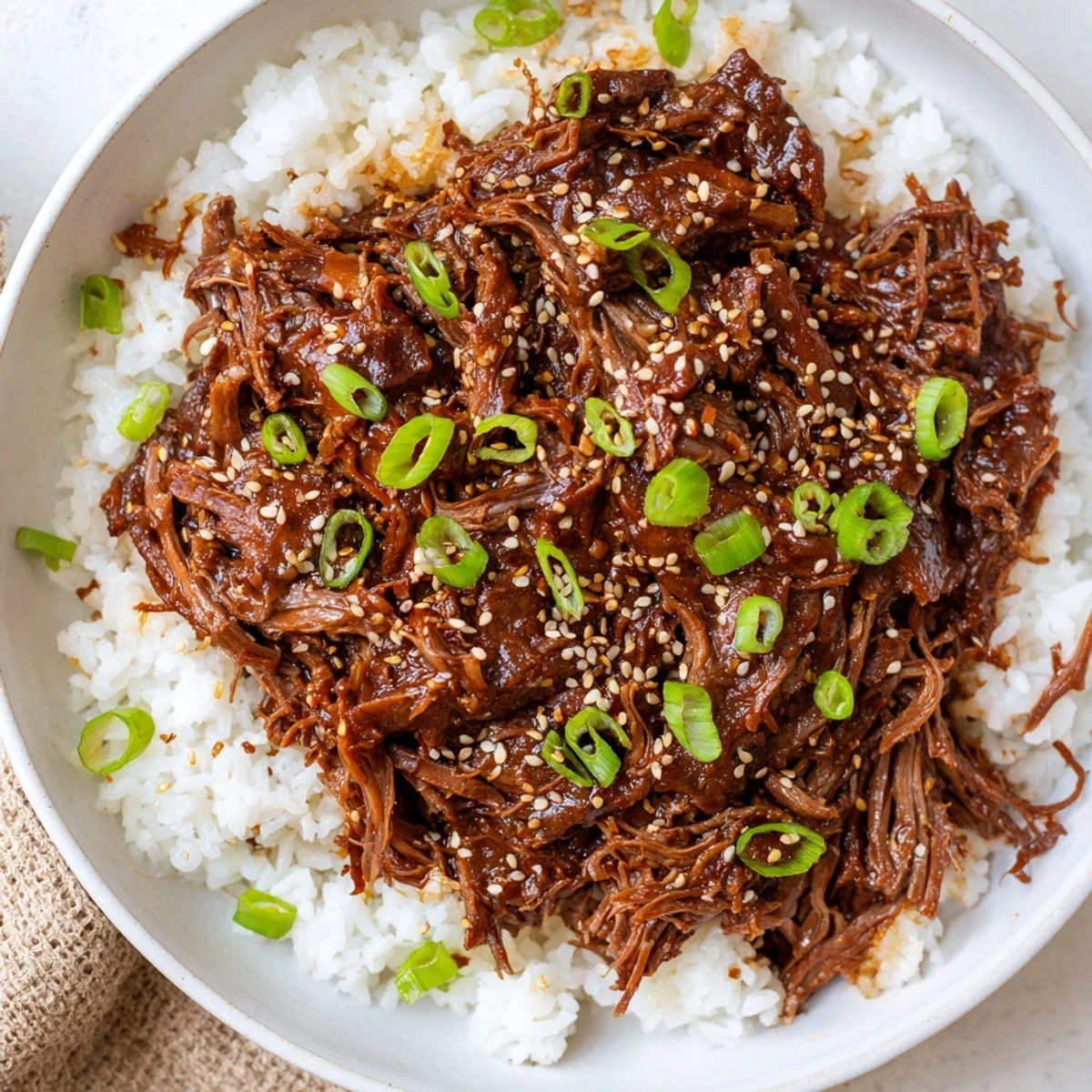 Tender shredded Slow Cooker Korean Beef piled high in lettuce wraps, garnished with sesame seeds and a slice of red chili.