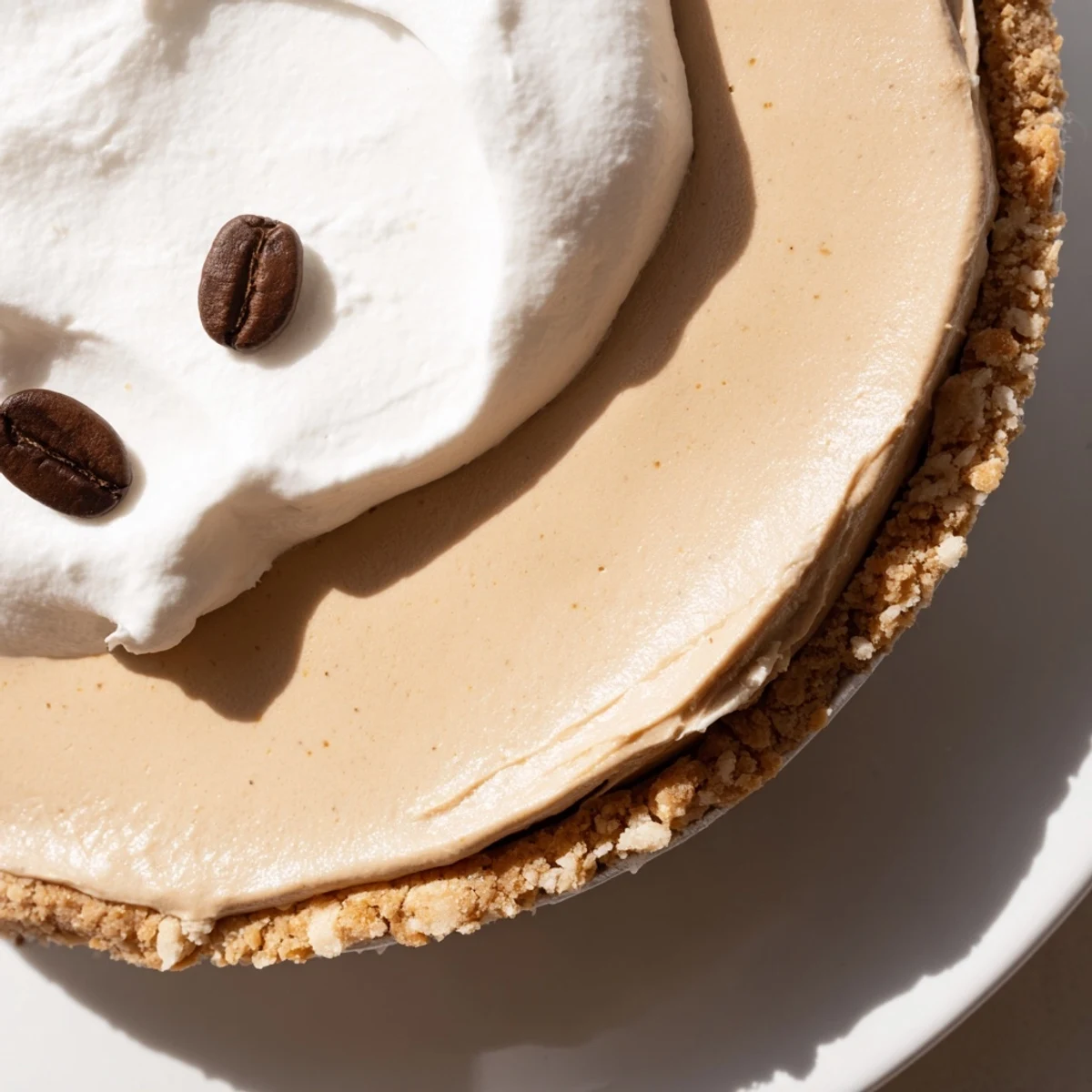 The chilled Keto Cold Brew Coffee Pie features a nutty crust and velvety coffee filling, served on a white plate with a rustic backdrop.