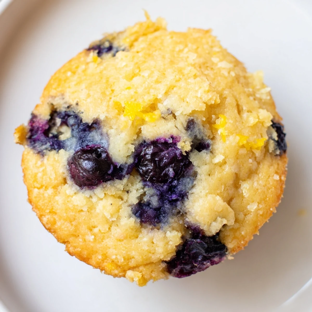 A stack of golden-brown Sourdough Blueberry Muffins on a rustic wooden board with fresh berries nearby.