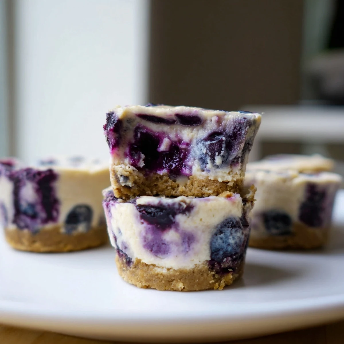 A plated tray of chilled Blueberry Cheesecake Protein Bites, garnished with fresh blueberries and a light dusting of lemon zest.
