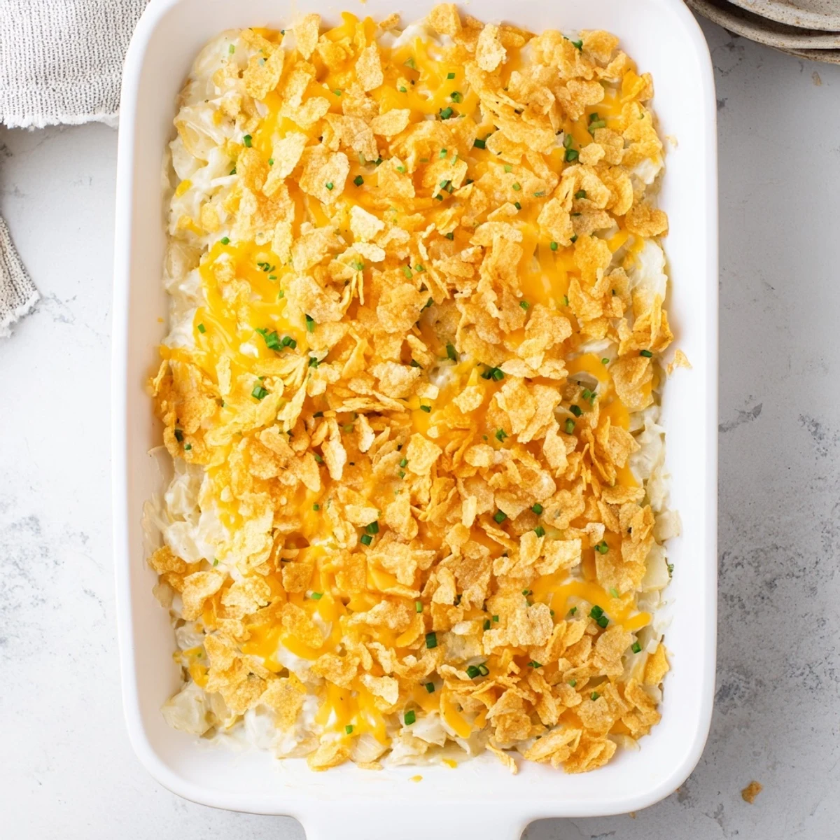 A golden Funeral Potatoes with Hashbrowns casserole bubbling in a 9x13 dish with a crunchy cornflake topping.
