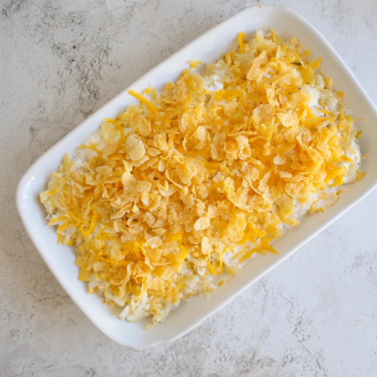 Comforting Funeral Potatoes with Hashbrowns casserole with a crispy topping, paired with roasted ham on a festive plate.