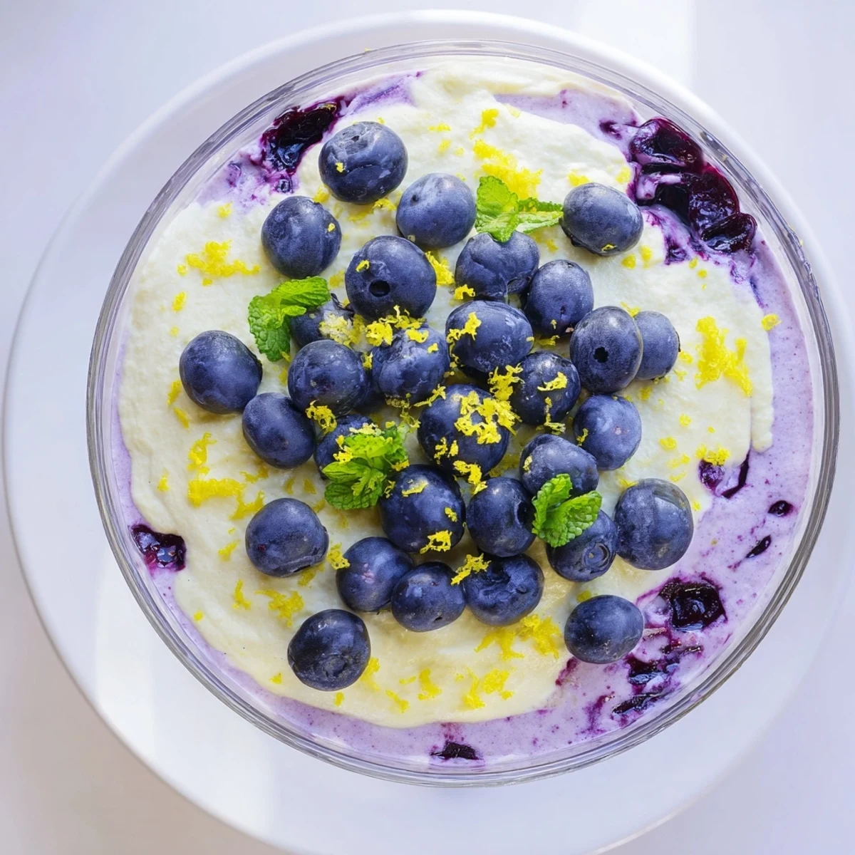 A vibrant glass of Lemon Blueberry Mousse garnished with fresh berries, lemon zest, and a mint leaf.