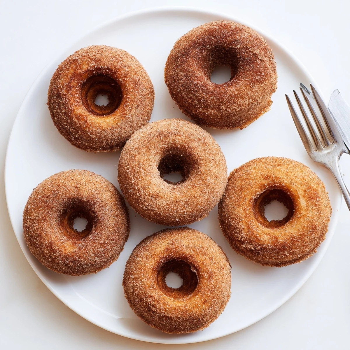 A platter of warm, baked Delicious Baked Cinnamon Sugar Donuts glistening with sweet buttery coating, ready for breakfast.