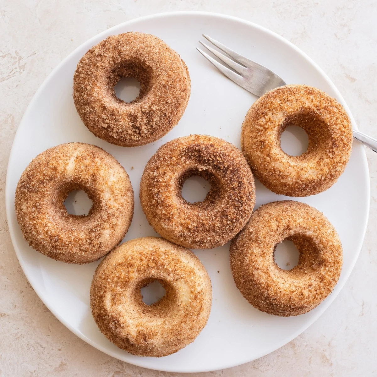 Close-up of Delicious Baked Cinnamon Sugar Donuts dusted with cinnamon sugar, served alongside a hot cup of coffee.
