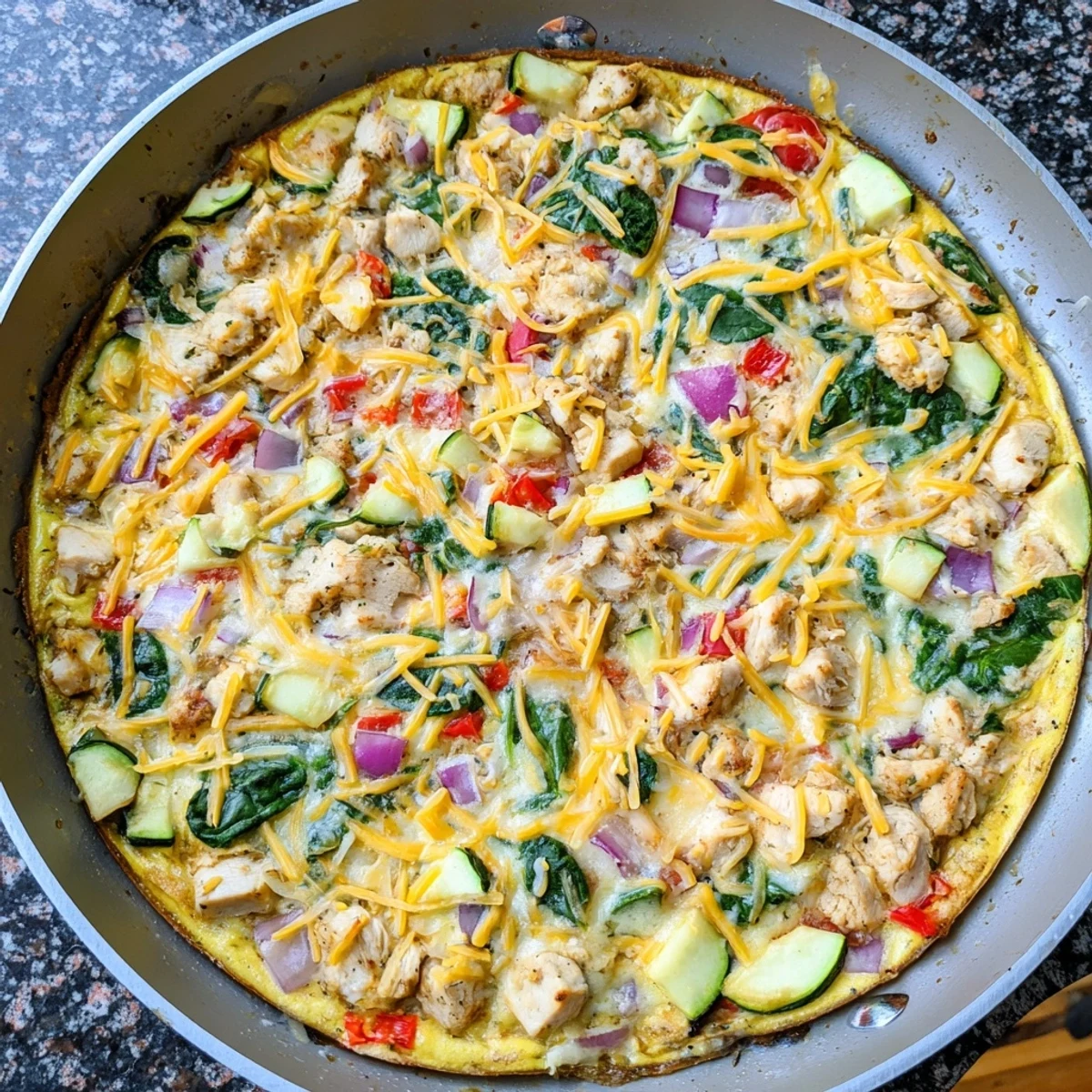 Close-up of a sliced Chicken and Vegetable Frittata showing fluffy eggs, spinach, and melted cheese on a plate.
