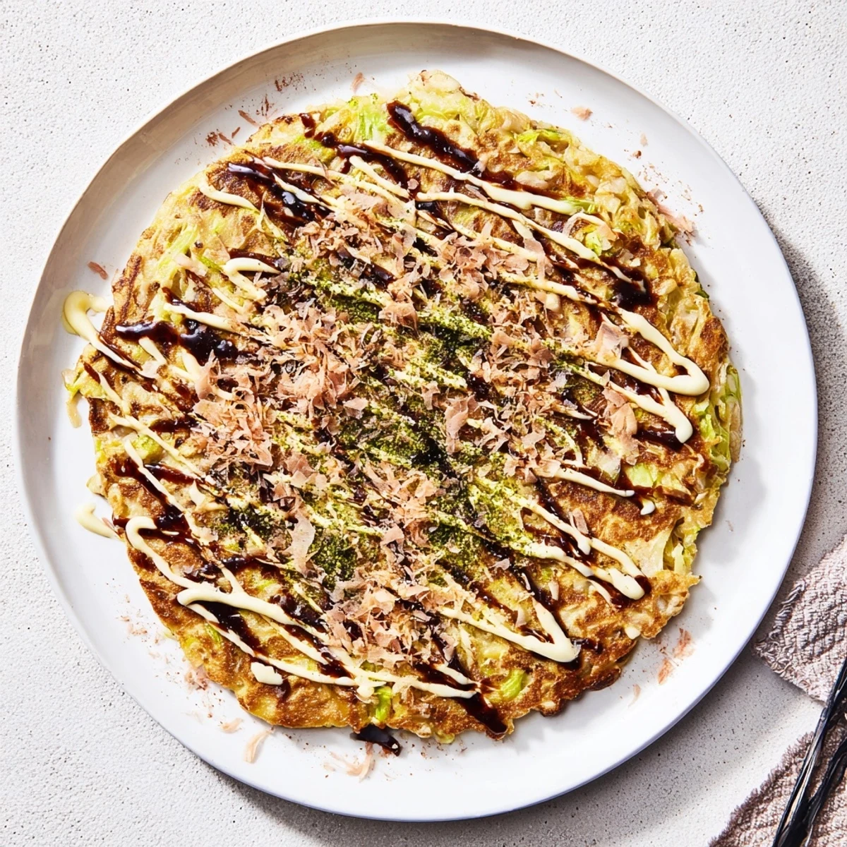 Crisp-edged Chicken Okonomiyaki sizzling in a skillet, filled with shredded cabbage and tender chicken pieces for dinner.
