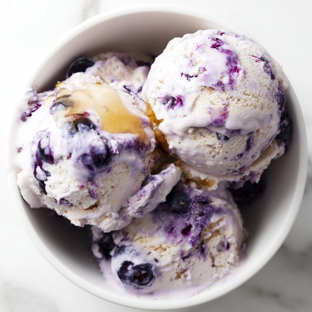 Blueberry Cottage Cheese Ice Cream scoops in a clear glass dish, showing the smooth texture and berry swirls.