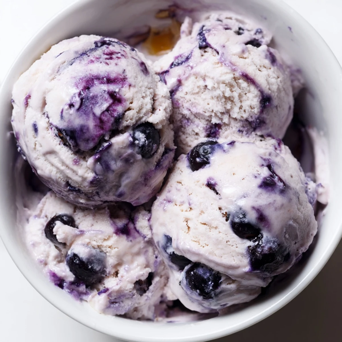Creamy Blueberry Cottage Cheese Ice Cream in a white bowl, topped with fresh blueberries and a mint sprig.