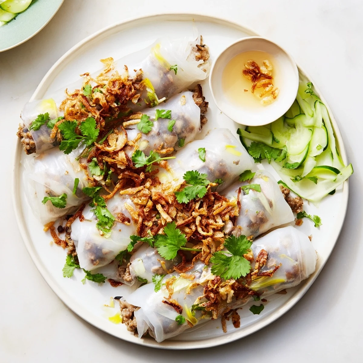 Thin, silky Banh Cuon rice rolls filled with savory pork and wood ear mushrooms, topped with fresh herbs.