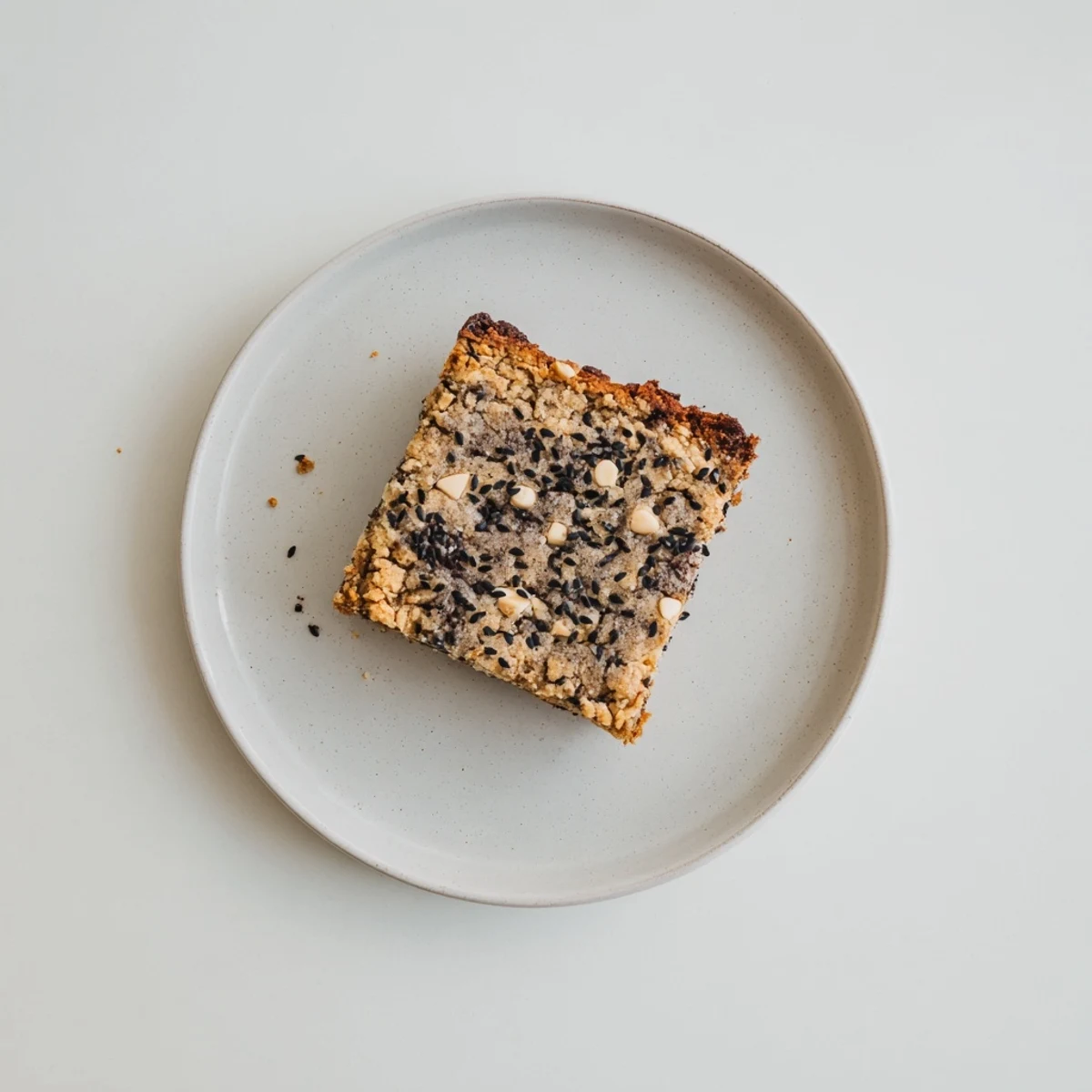 Gooey Black Sesame Blondies served warm on a marble board, garnished with toasted sesame seeds and a side of vanilla ice cream.