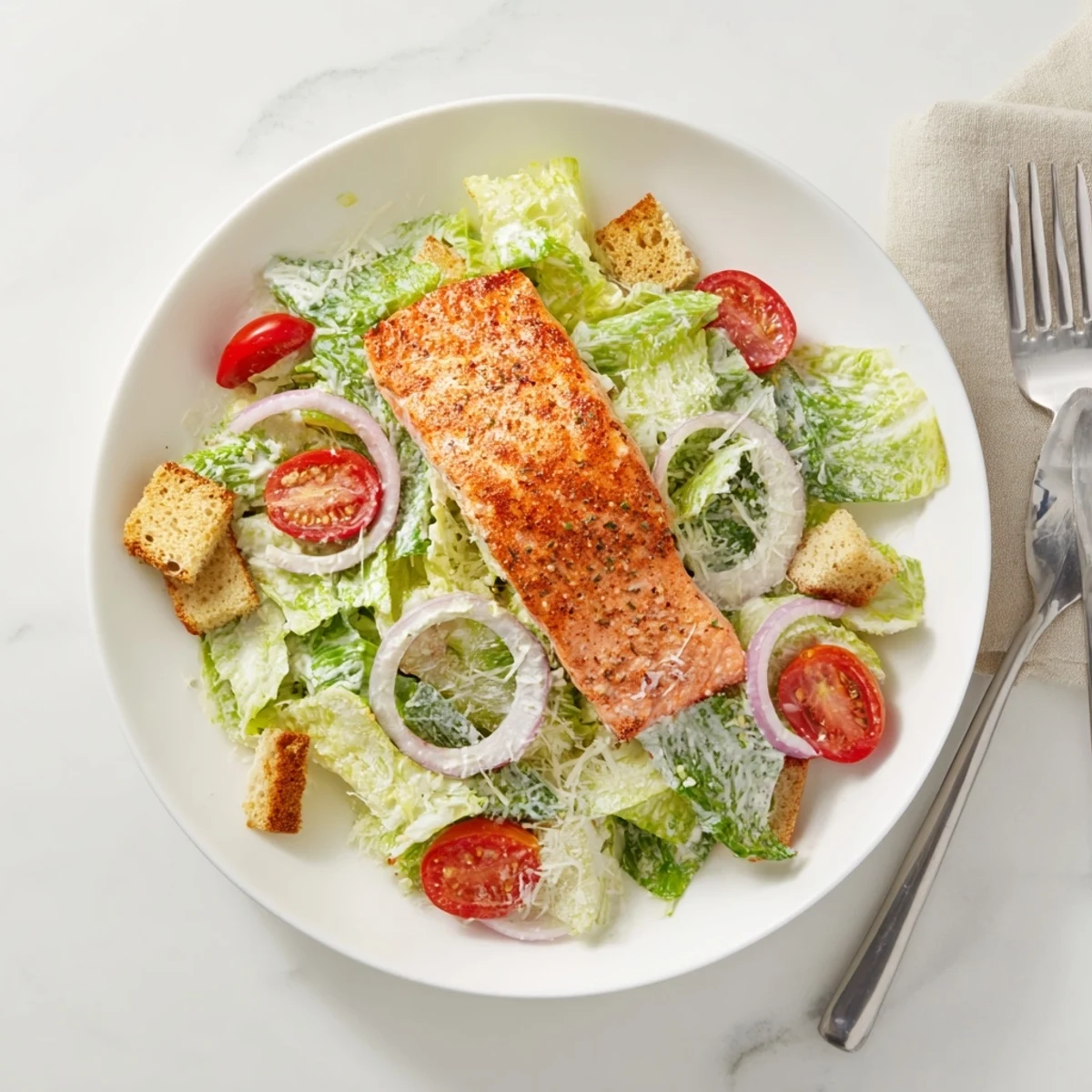 Fresh salmon fillets resting atop Caesar salad with crunchy croutons and shaved Parmesan