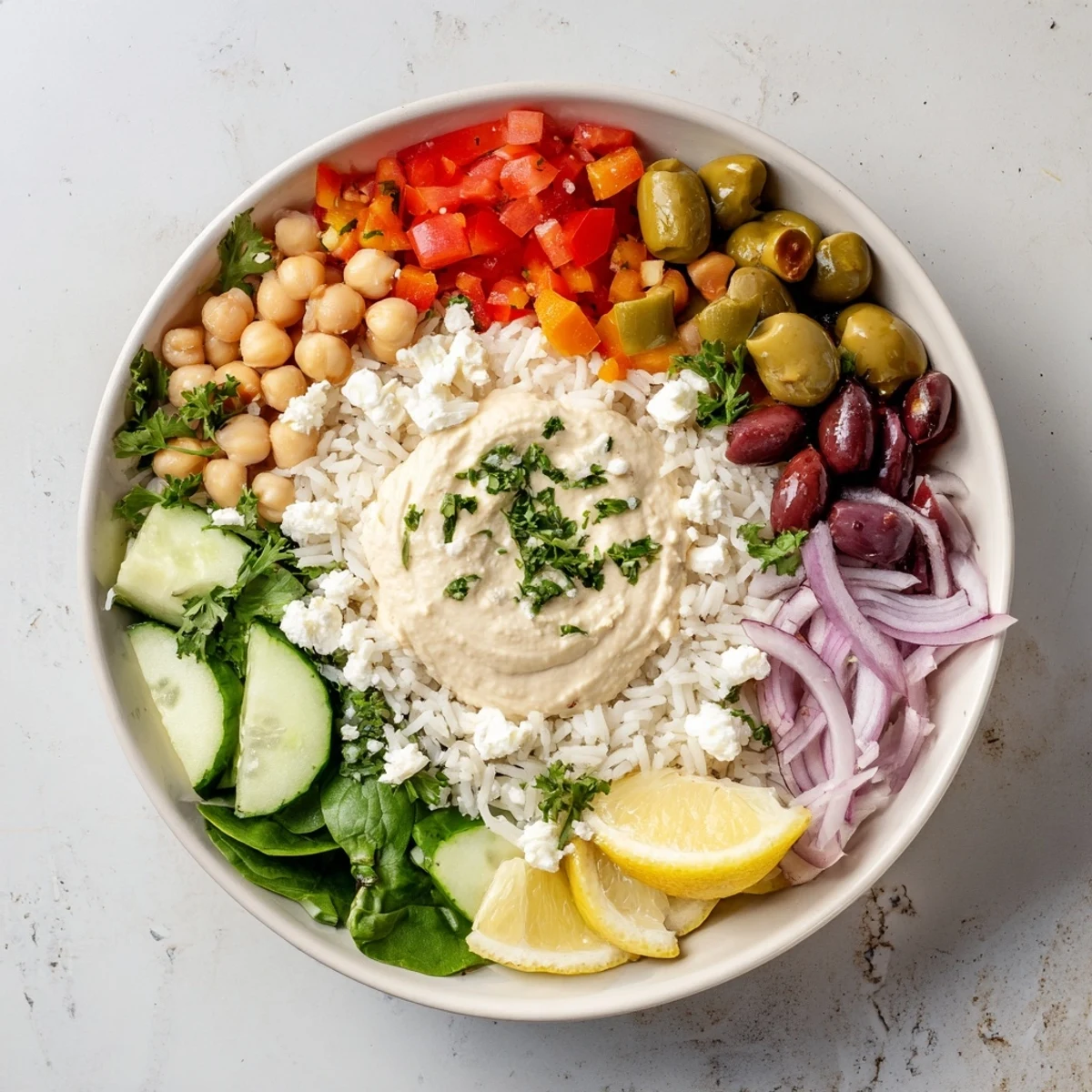 Vibrant Mediterranean rice bowl topped with fresh vegetables, creamy hummus and zesty lemon tahini dressing