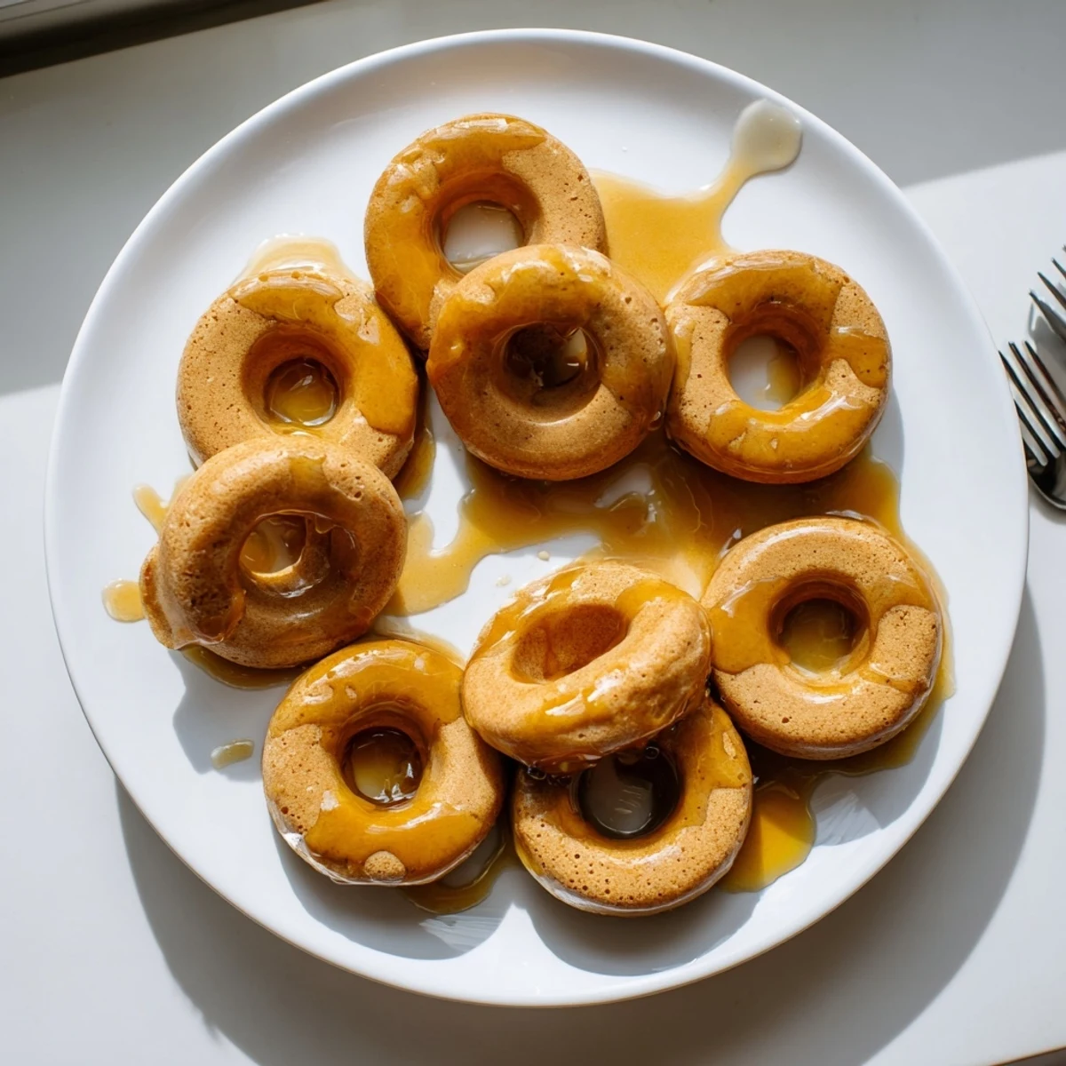 Golden maple pumpkin mochi donuts with sweet glaze drizzle on a wire rack