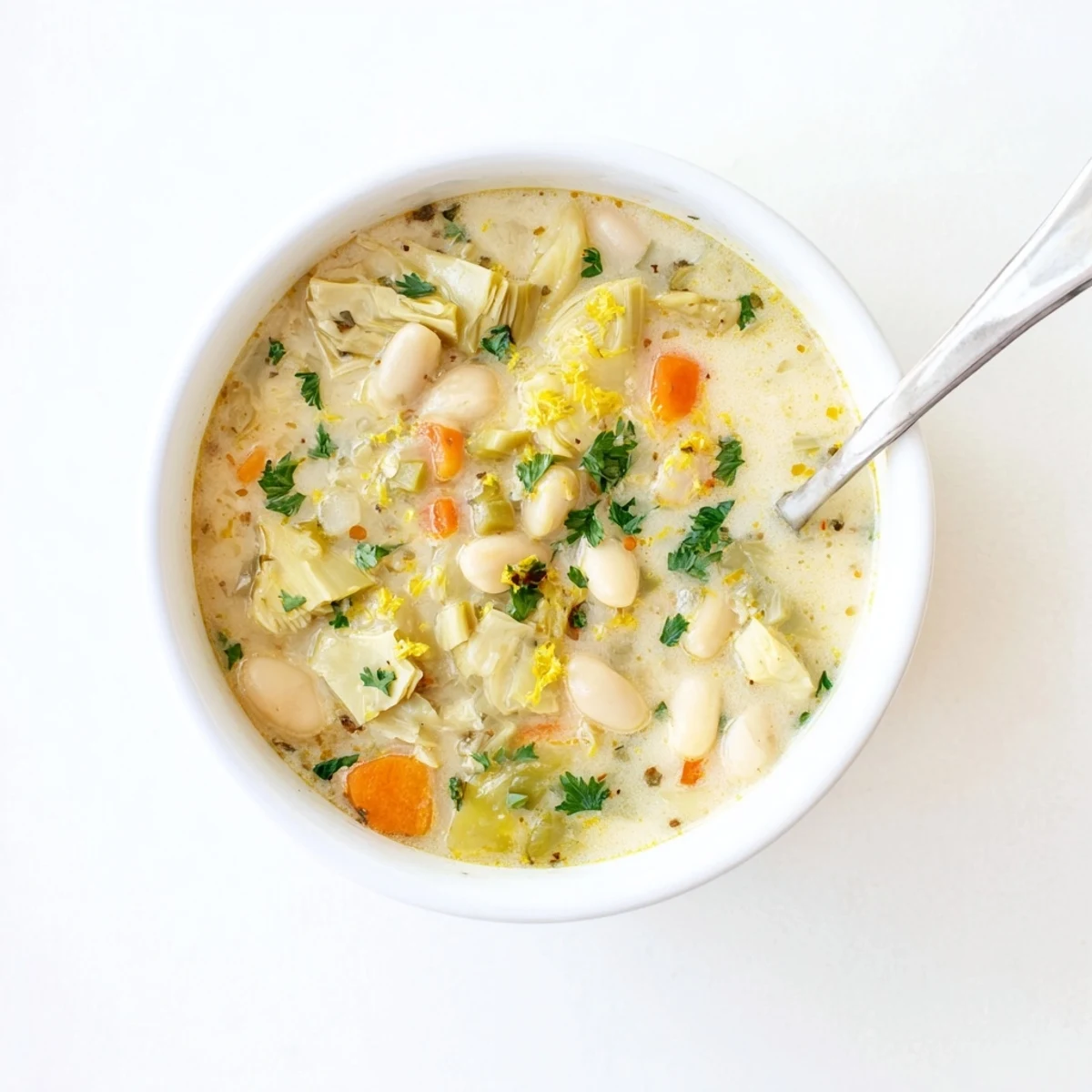 Creamy Lemony Tuscan Artichoke soup garnished with fresh parsley and lemon wedges in a rustic bowl