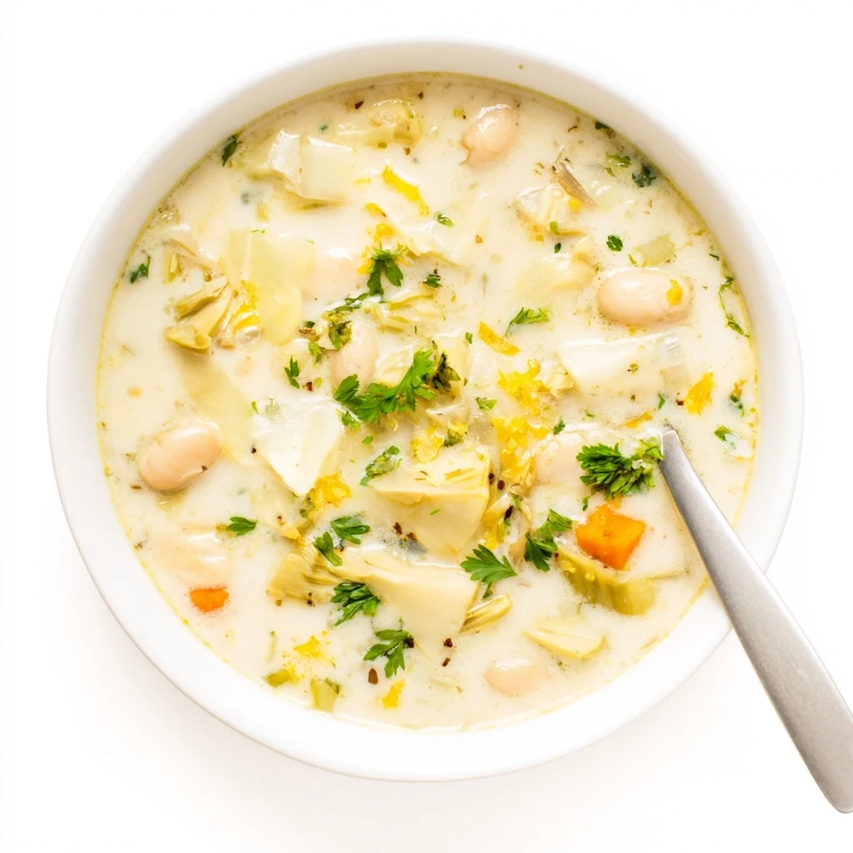 Steamy Lemony Tuscan Artichoke Soup sprinkled with red pepper flakes and Parmesan cheese on a wooden table