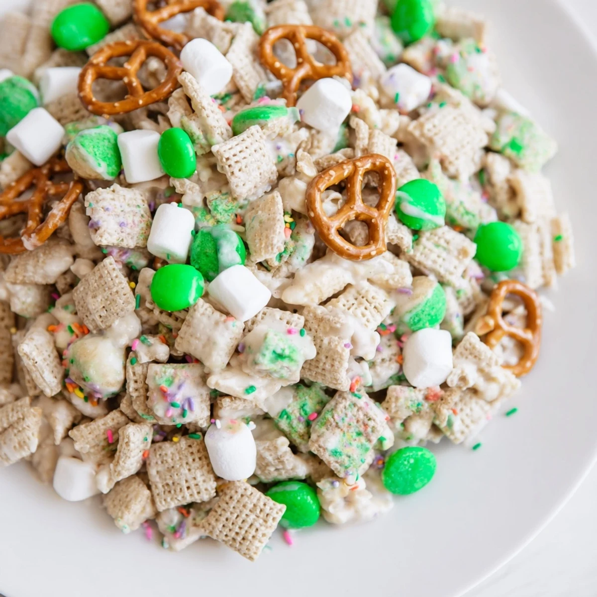 White chocolate drizzled Leprechaun Bait featuring pretzels, popcorn, and festive green M&Ms