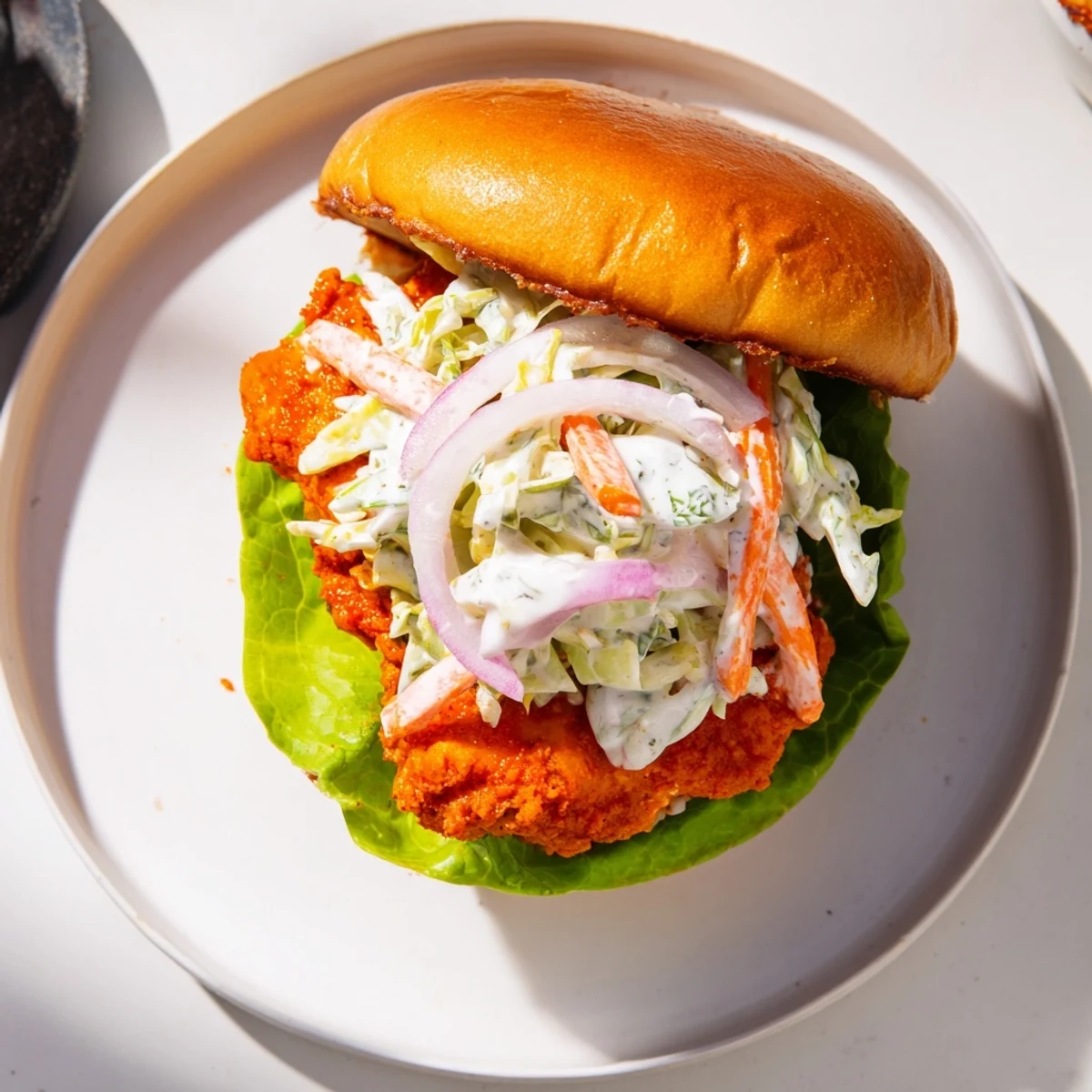 Spicy buffalo fried chicken breast topped with creamy cabbage slaw in soft sandwich