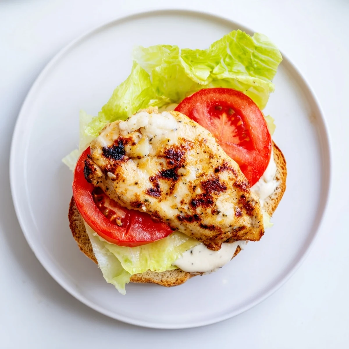 Juicy marinated chicken breast sandwich with fresh garden vegetables and tangy garlic mayonnaise on golden toasted bread