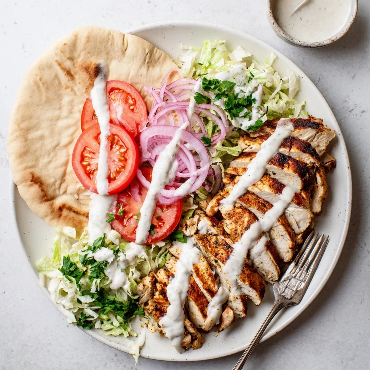 Tender marinated chicken shawarma stacked in a warm flatbread with crisp onion, parsley, and homemade white garlic toum sauce