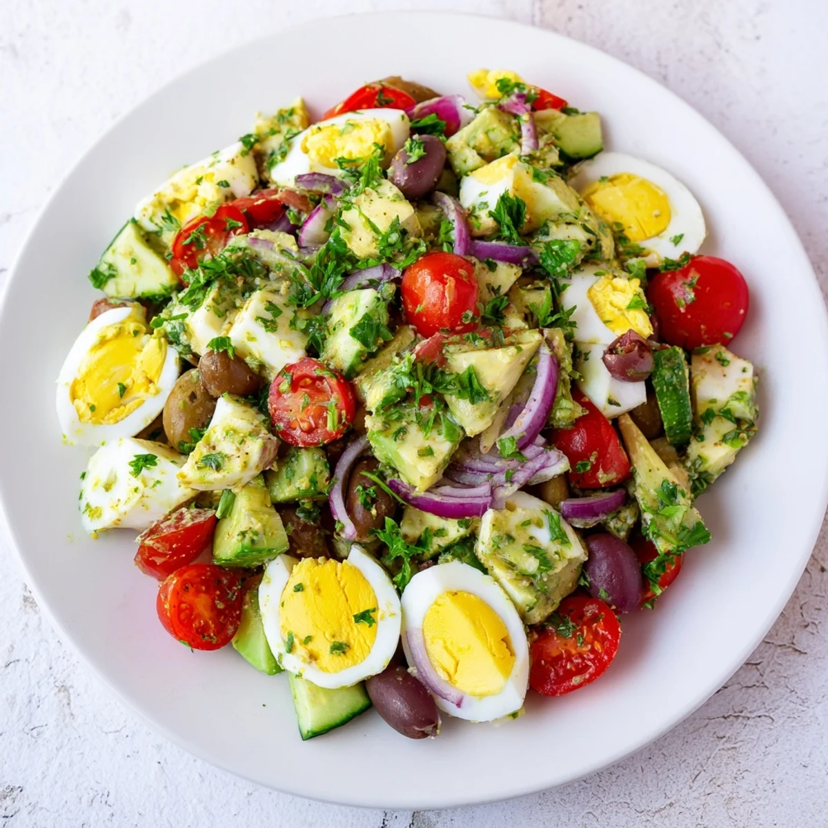 Healthy avocado egg salad bowl featuring ripe avocado chunks and Mediterranean dressing drizzle