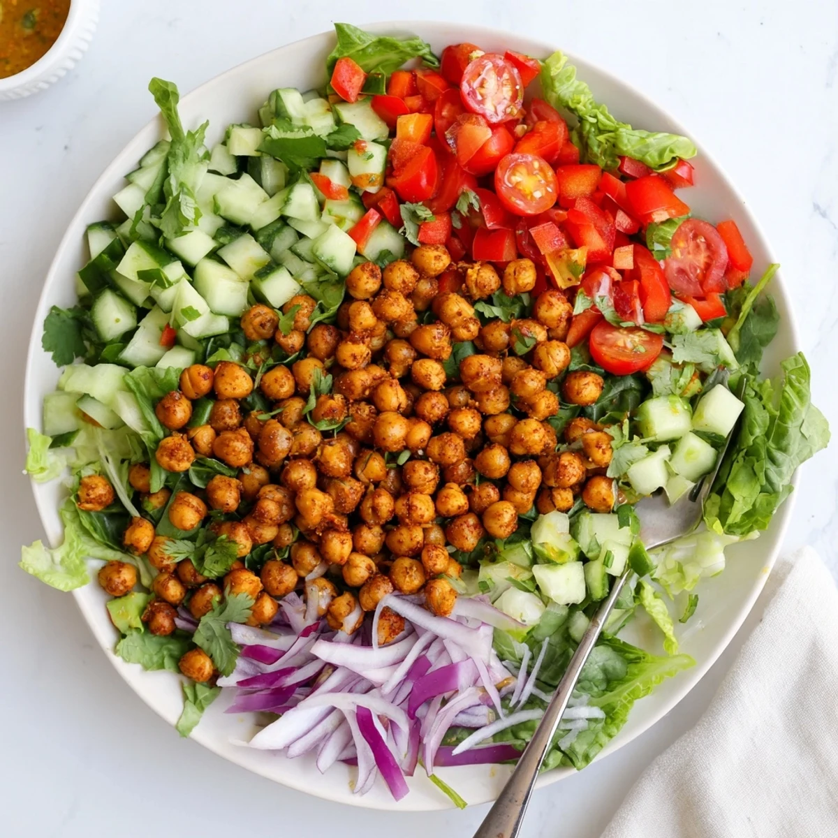 Golden roasted chickpeas with chili lime spices atop fresh mixed greens and colorful vegetables