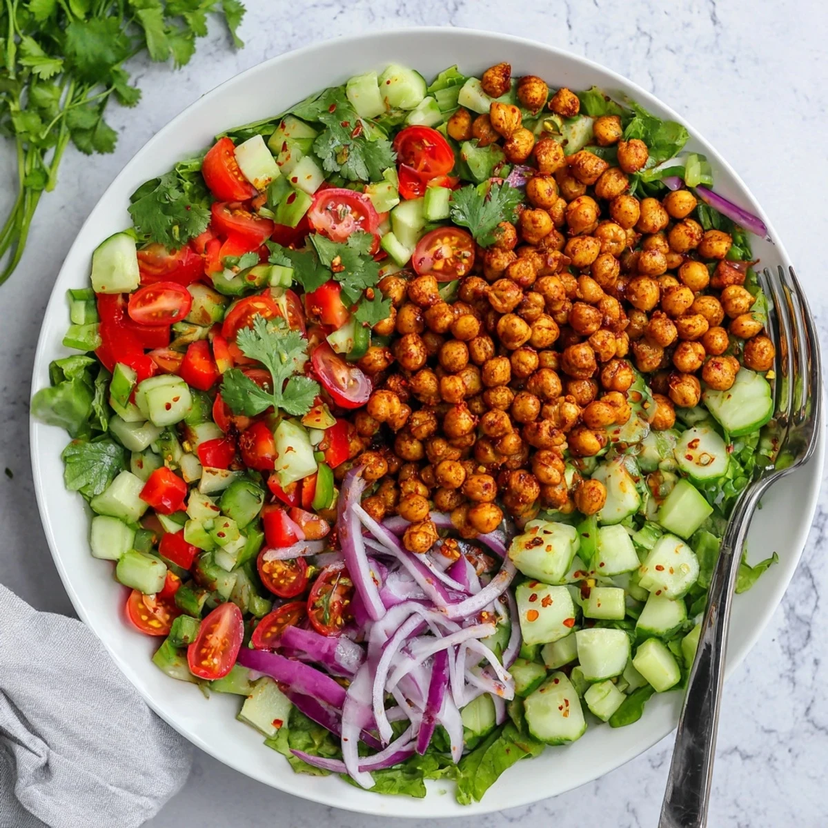 Vibrant salad bowl featuring crispy spiced chickpeas over crunchy vegetables with tangy lime dressing