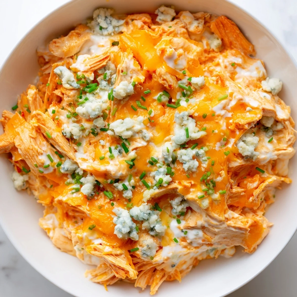 Creamy Crockpot Buffalo Chicken Dip topped with melted cheddar and fresh green onions