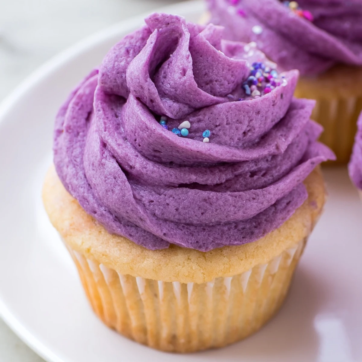 Vibrant purple grape soda cupcakes with tangy grape buttercream arranged on a decorative serving platter.