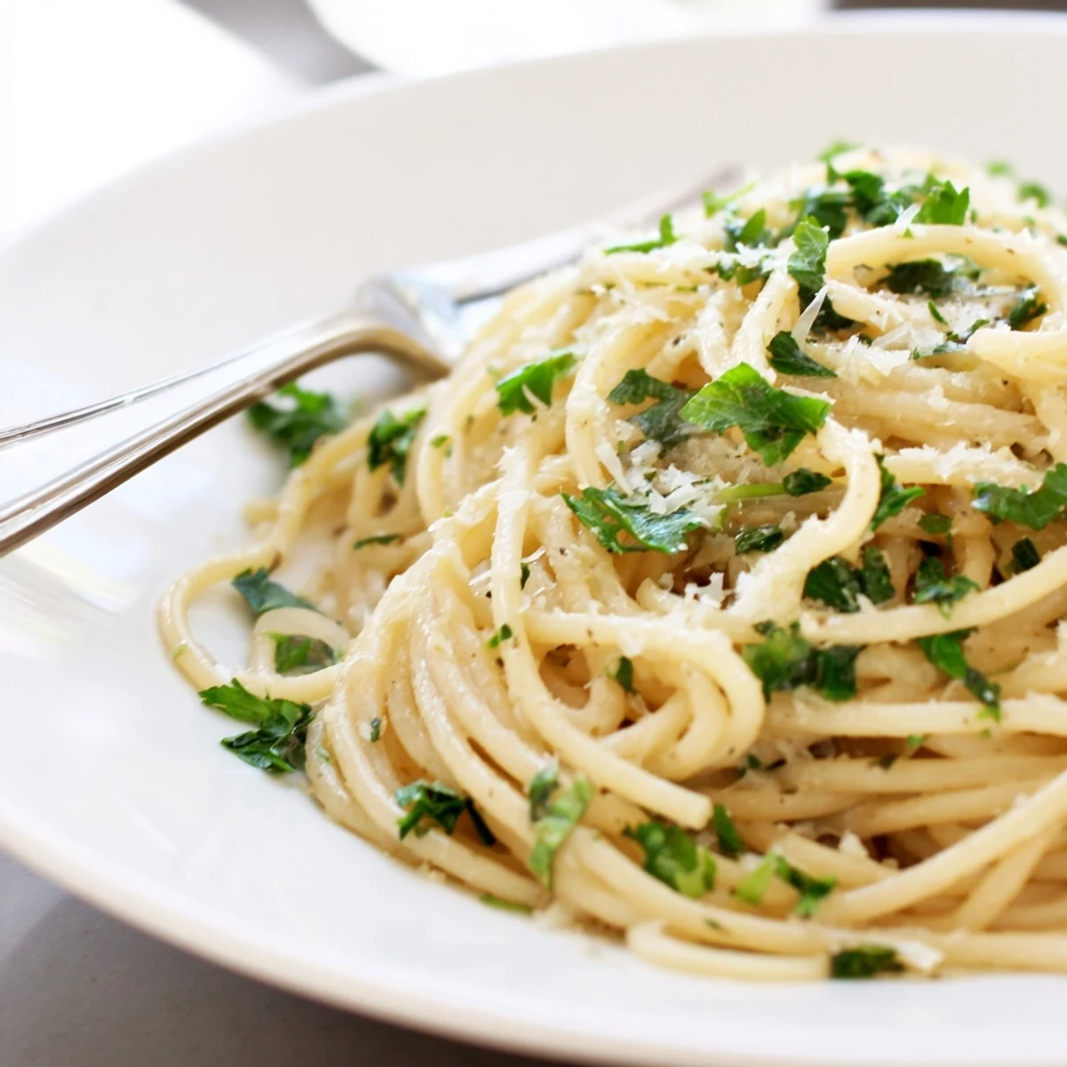 Steaming plate of garlic butter pasta tossed in silky sauce with lemon zest and cracked pepper