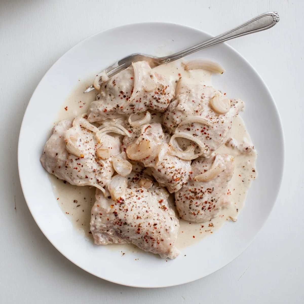 Succulent Crockpot chicken thighs plated in a thick, savory cream gravy perfect over mashed potatoes.