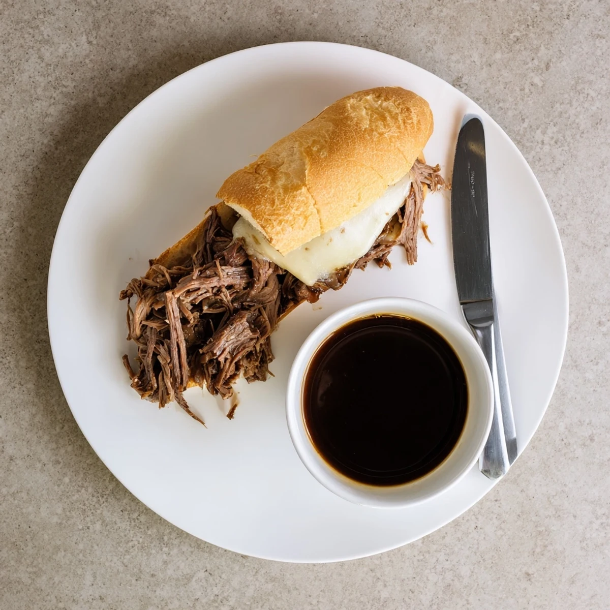 Crockpot French Dip Sandwiches with savory au jus for dipping on a rustic wooden board