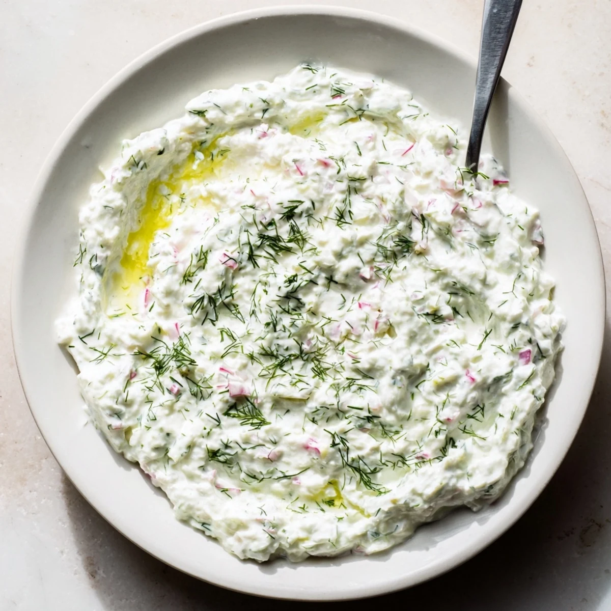 Refreshing healthy radish tzatziki dip garnished with mint and olive oil swirl