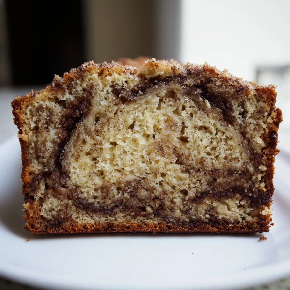 Golden Cinnamon Sugar Swirl Banana Bread sliced thick on a rustic wooden cutting board