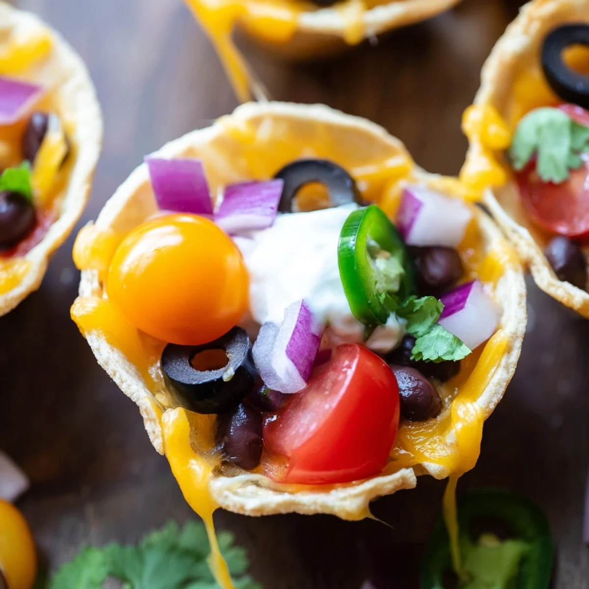 Golden cheesy nacho cups bubbling with melted cheddar and colorful fresh toppings