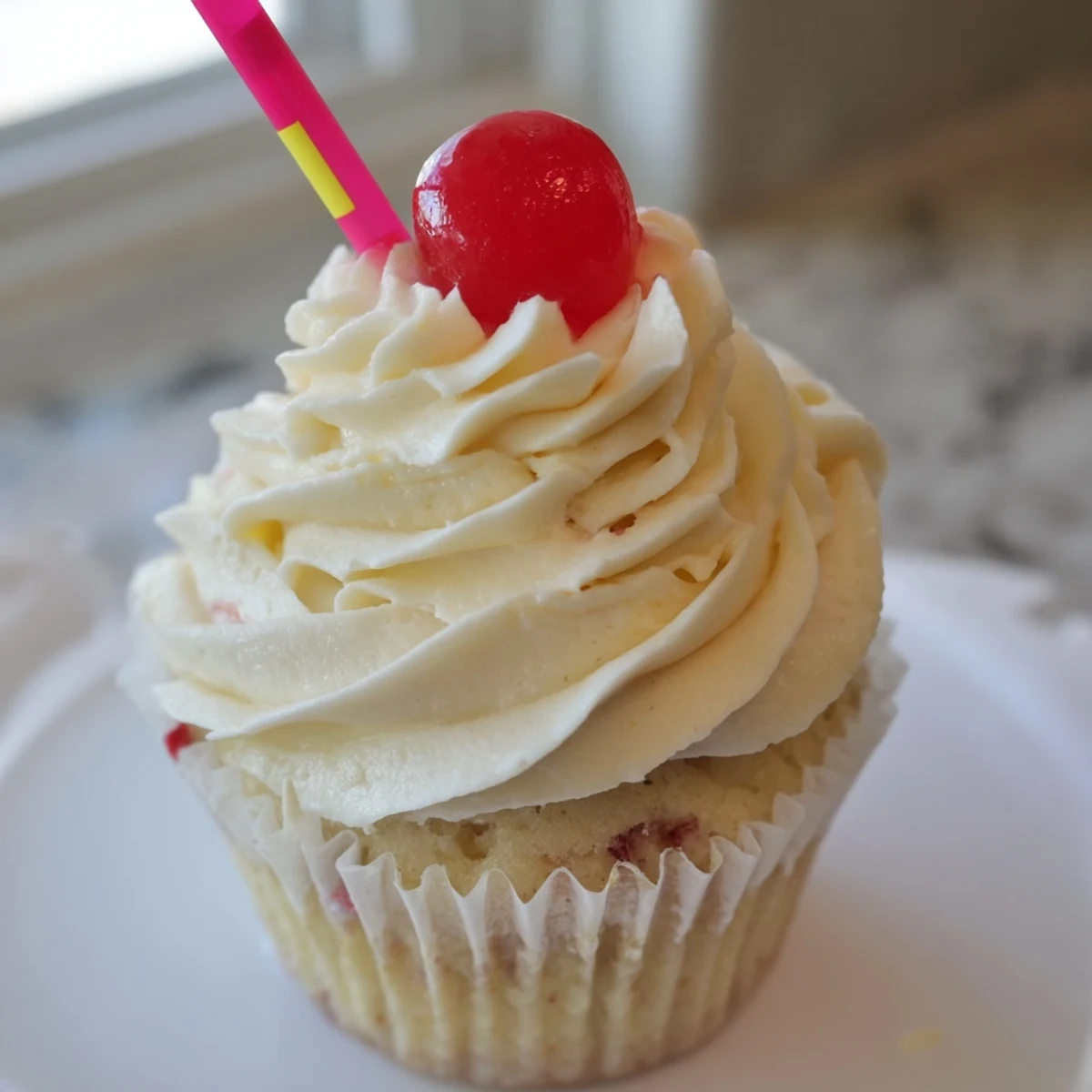 Golden banana milkshake cupcakes topped with creamy swirled frosting and bright red maraschino cherries