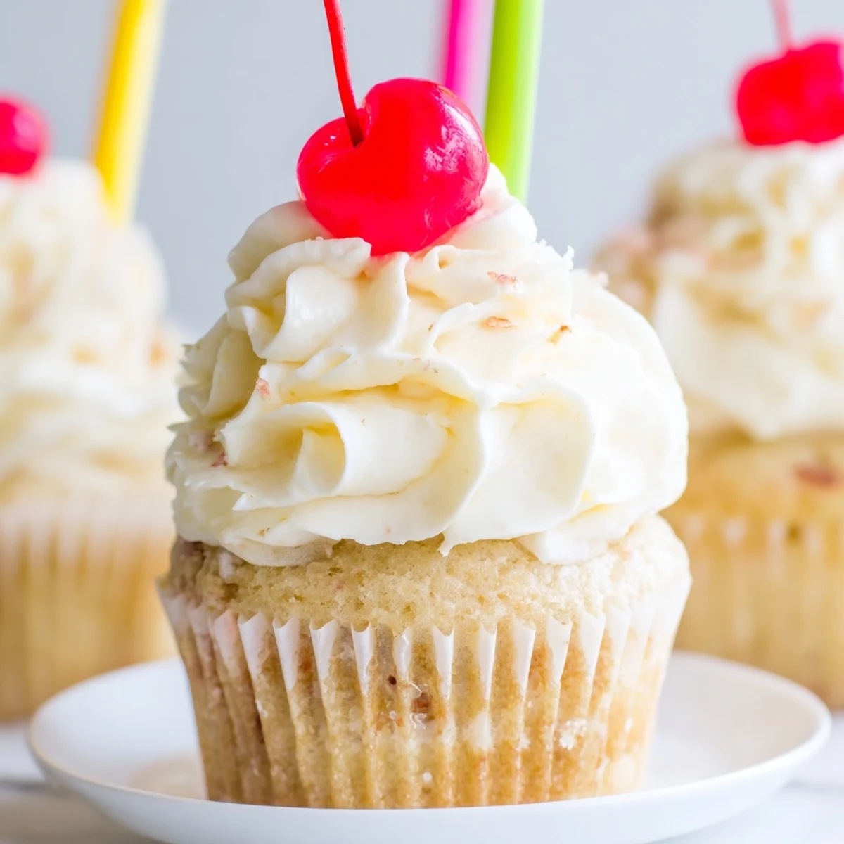 Moist banana milkshake cupcakes with fluffy vanilla frosting piped high and decorative paper straws inserted