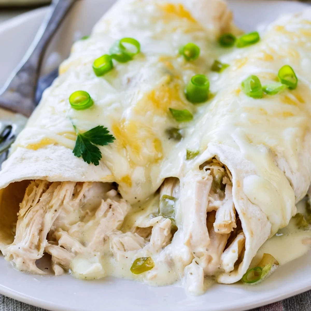 Creamy White Chicken Enchiladas bubbling with melted cheese, golden edges, garnished cilantro.