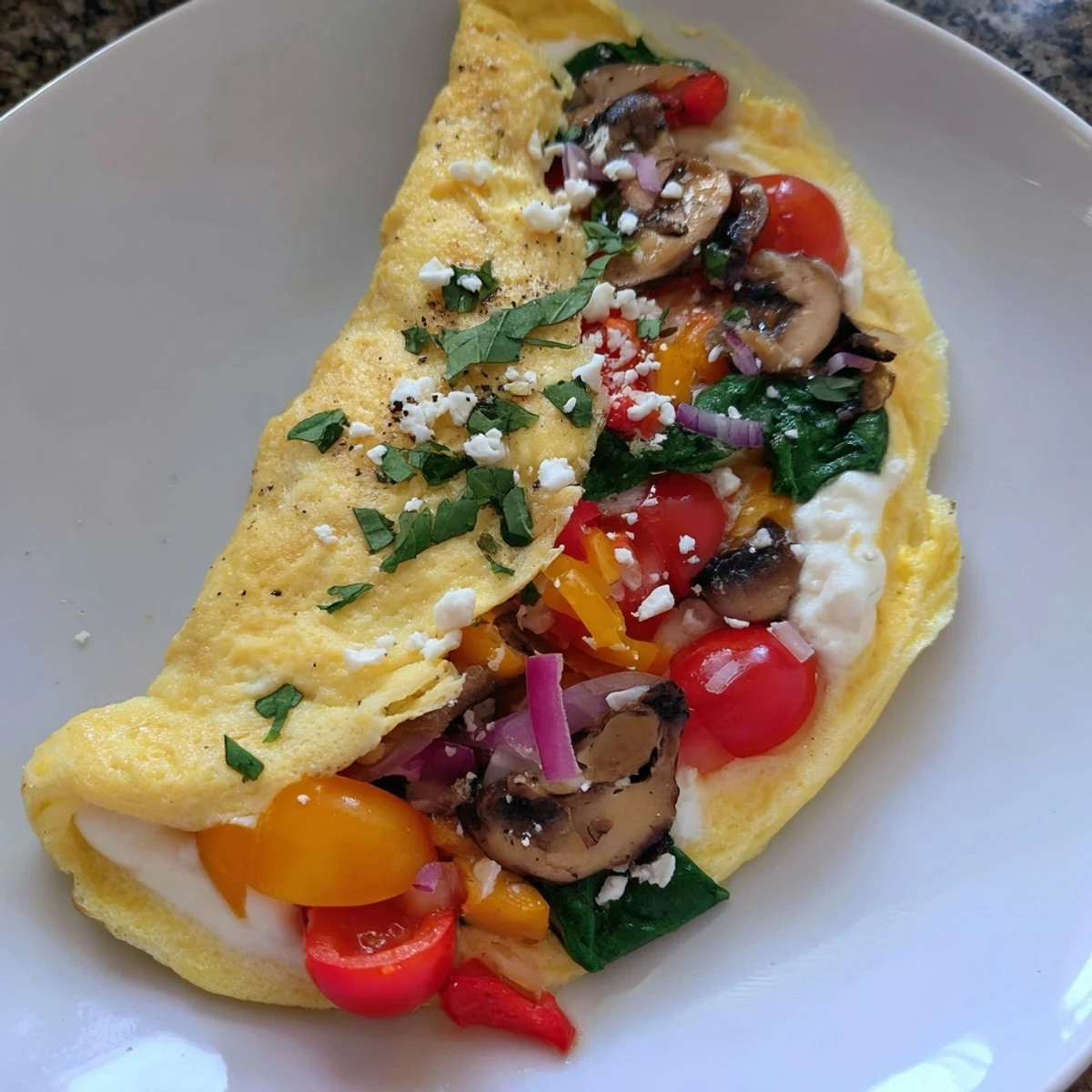 Light Egg White Omelette with Vegetables garnished with crumbled feta and parsley.  